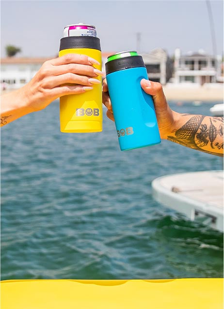 Two 12oz Slim “Bob's Chillin” Can Coolers being used to cheers on a boat.
